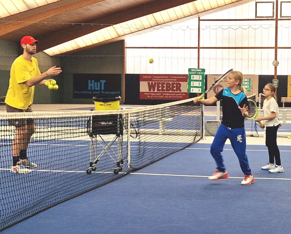Trainer spielt Kindern Bälle zu